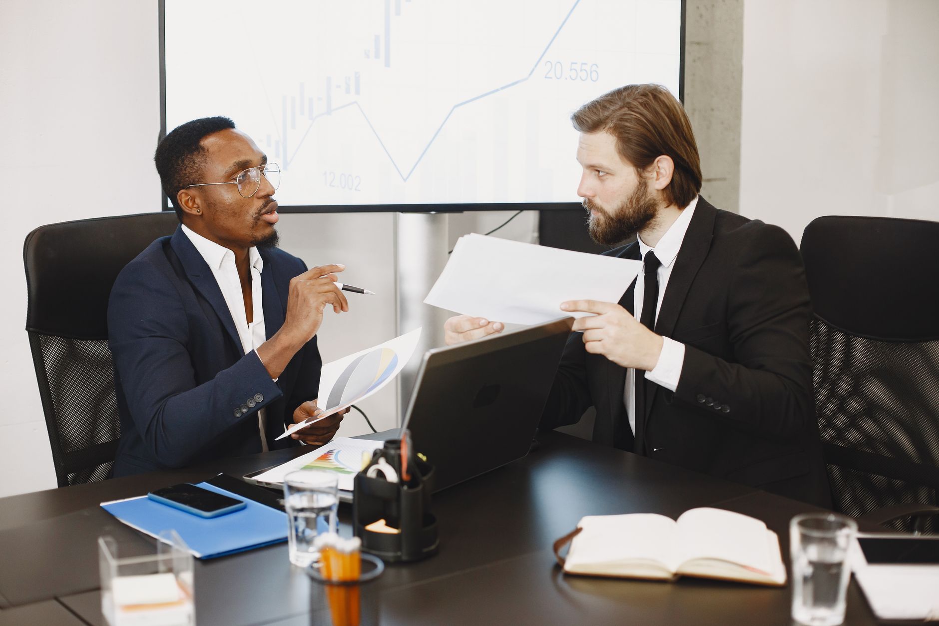 Two business professionals engaged in a planning meeting, discussing documents in a modern office setting. — The Leadership a